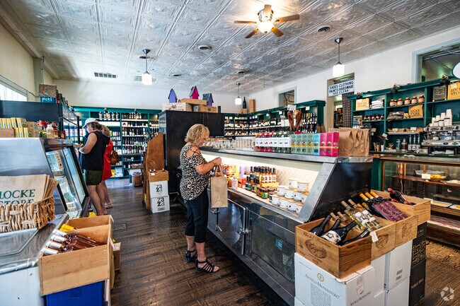 Inside the Locke Store in Millwood, shoppers browse local wines, specialty foods, and fresh deli items beneath a vintage tin ceiling.