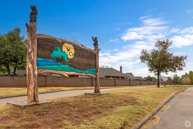 A carved wooden sign welcomes visitors to the Canadian Estates neighborhood.