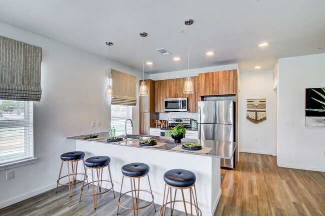 Kitchens feature oak upper and white lower cabinetry, grey quartz countertops, white subway tile backsplash, kitchen island or breakfast bar, and luxury vinyl plank flooring