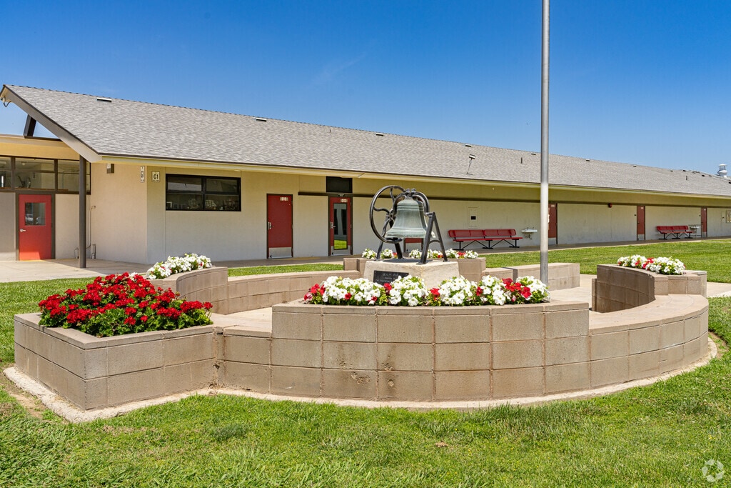 A small flower garden surrounds an old bell at the entrance to Tipton Elementary School.