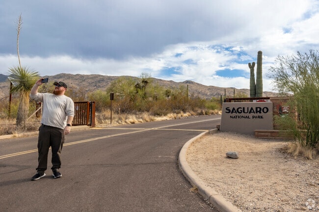 A visitor takes a selfie at the Saguaro National Park entrance sign near Saguaro Canyon, Tucson.