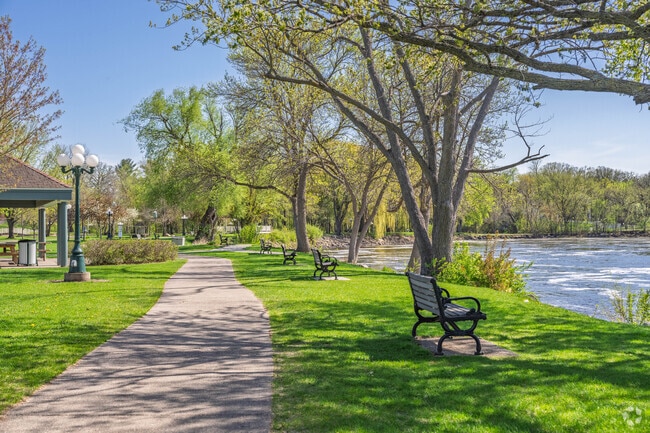 Walking paths and park benches line the riverfront in the city of Little Falls.