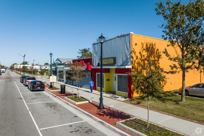 A man stands outside local shops featuring vibrant colors in the downtown area of Marshall.