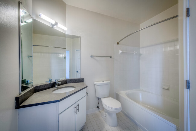 Renovated Package II bathroom with white cabinetry, grey quartz countertop, and hard surface flooring