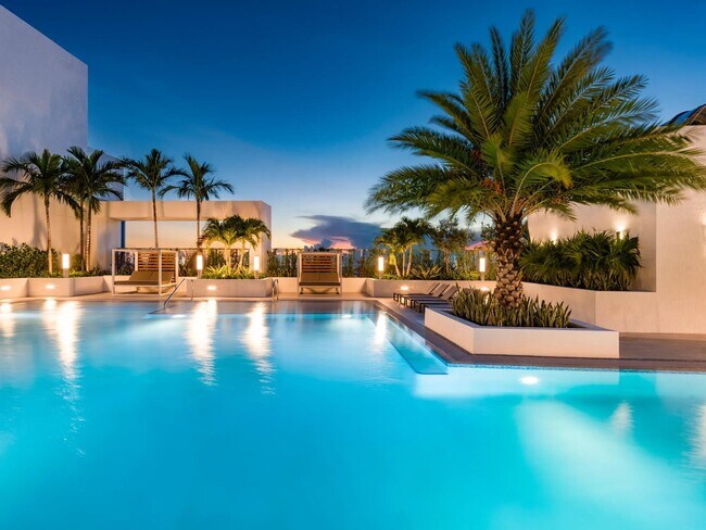 Twilight elegance awaits at Modera Riverside’s rooftop pool, where palm-lined waters meet the glow of the Miami skyline.