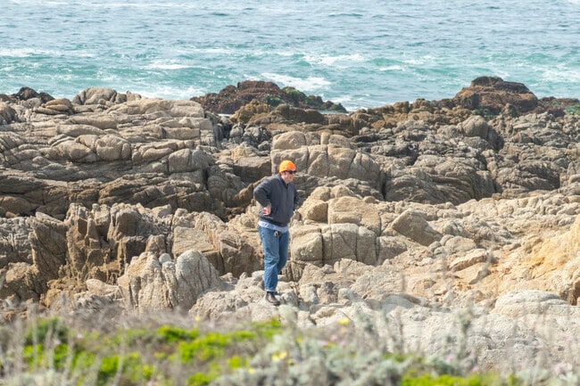 A man walking in the rocks of Asilomar State Beach in the Pacific Grove neighborhood.