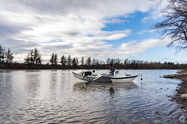 An Evergreen angler in a drift boat with his dog on the Flathead River is hoping to catch a trout.