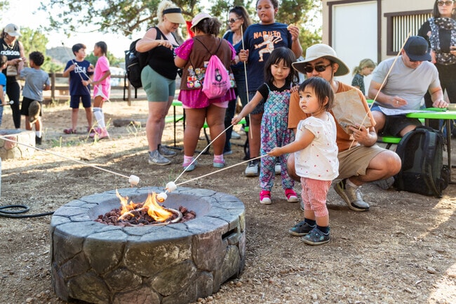 A dad helps his daughter make s'mores at Fireside Nights.