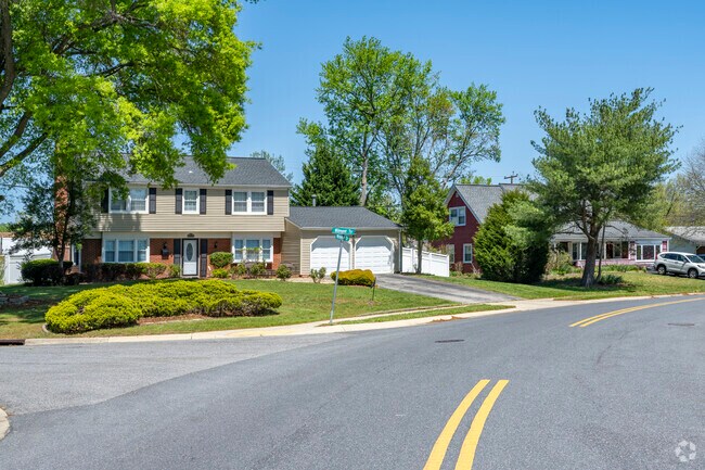 A colonial revival sits next to a cape Cod, both have spacious yards and enclosed garages.