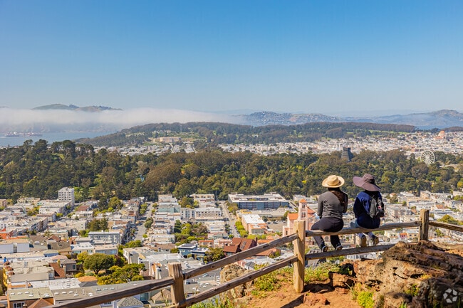 Two friends sit and enjoy the view of Golden Gate Park and Inner Sunset from Goldview Park.