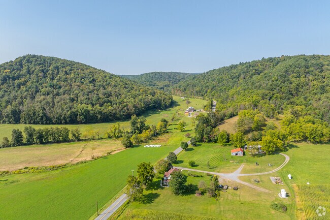 Farmland and homes with vast land sit in between mountains of greenery in Boggs Township.