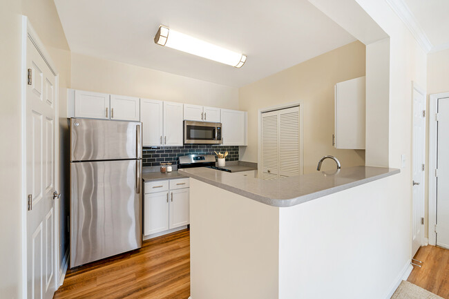 Renovated Package I kitchen with white cabinetry, grey quartz countertops, dark grey subway tile backsplash, stainless steel appliances, and hard surface flooring