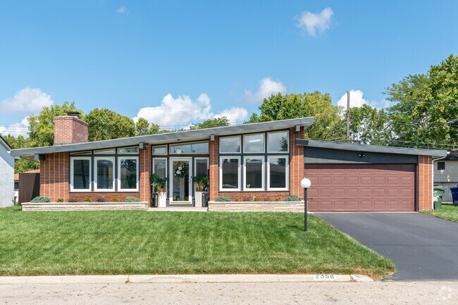 A modern ranch home in Teakwood features a well-manicured front yard.