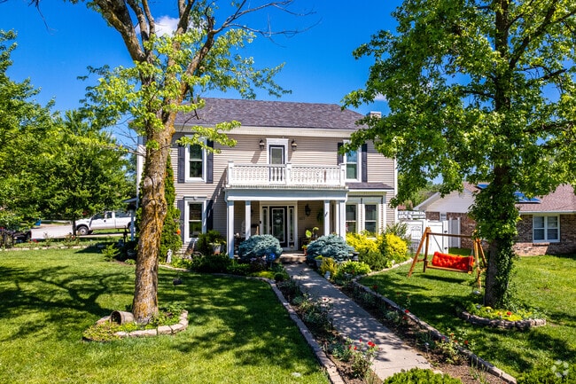 A large national style 2 story home with meticulous landscaping sits on a street in Polk County.