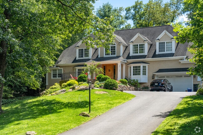Large colonial revival sits atop a hilly driveway.