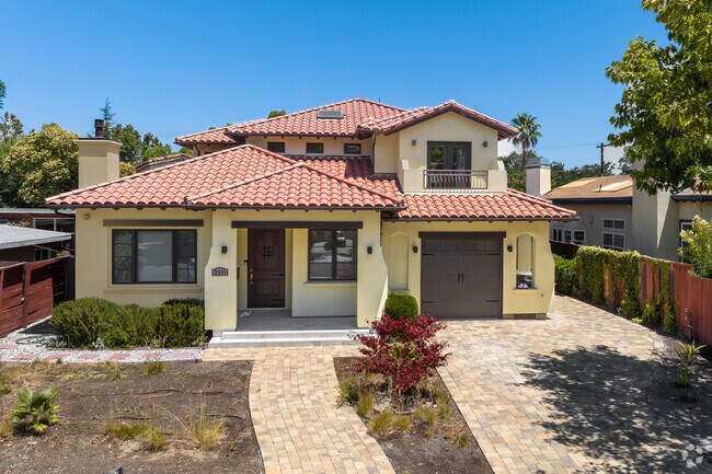 This soft yellow home has a terracotta roof and a beautifully laid stone sidewalk in Palo Verde.