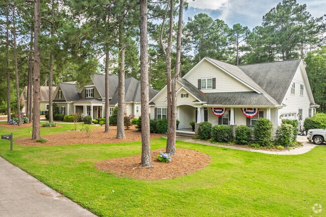 Homes in Pinehurst display patriotic decor and manicured yards along shaded streets.