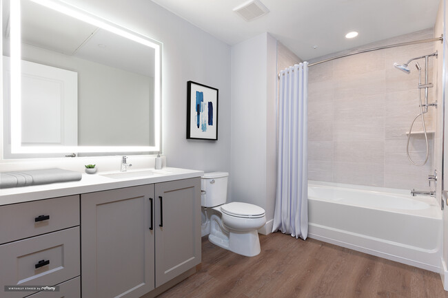 Signature Collection bath with grey cabinetry, white marble countertop, backlit mirror, and hard surface flooring