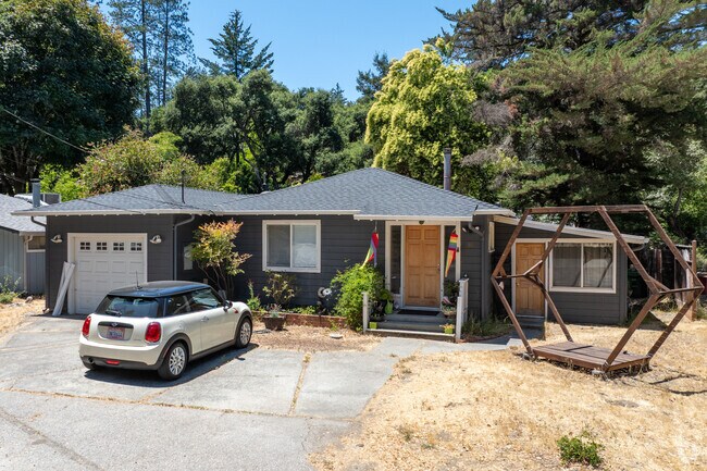 This mid-century ranch home in Felton features a low-slung roofline, cozy front porch, and attached garage set on a sunny lot with mountain trees in the backdrop.