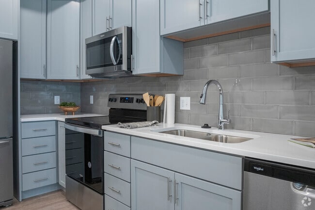 Kitchens feature quartz countertops, stainless steel appliances, and glass subway tile backsplashes