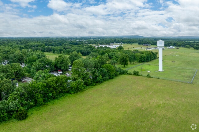 The Pryor Creek water tower stands tall above open fields and trees on the edge of town.