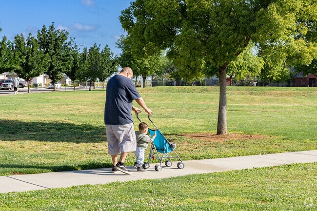 A grandfather walks his grandson along the sidewalks of Peter Malloch Park.