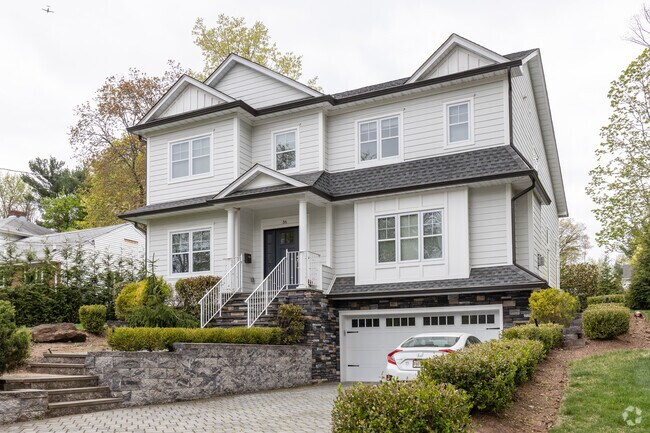 A colonial style house in Tenafly, NJ with a large garage.
