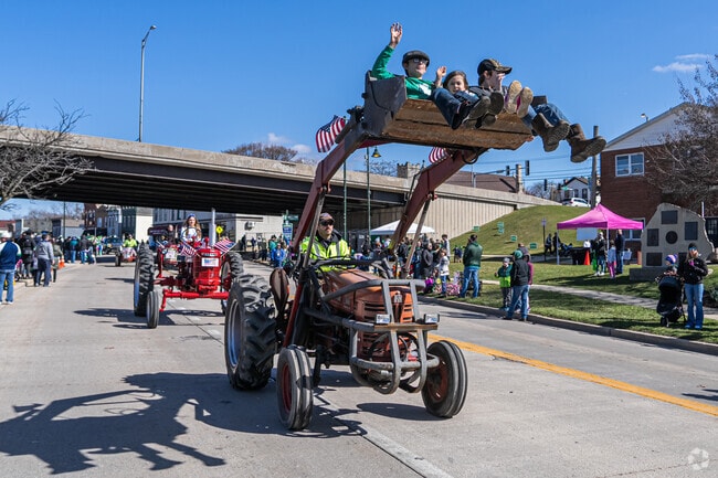 Children wave from a tractor bucket at the annual St. Patrick's Day Parade.