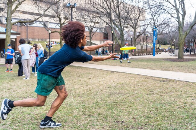 Two guys play catch with a yellow frisbee on the DePaul Quad.