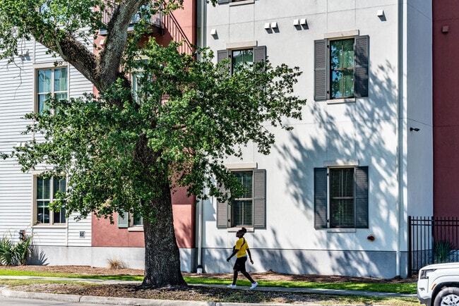 A person walking down the sidewalk in front of townhomes in the Iberville neighborhood.