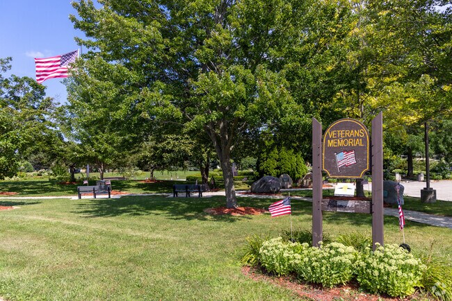The Veterans Memorial at Pritchard Park includes statues, flowers, and an American flag.