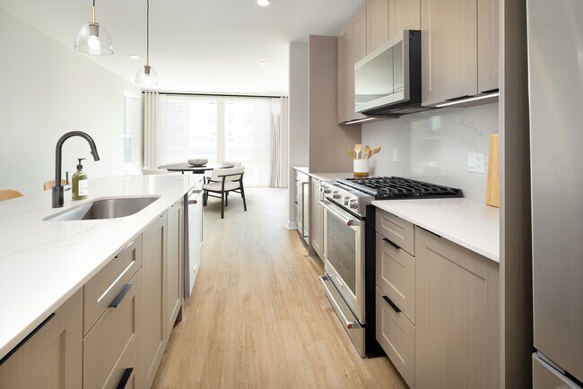 Signature Collection Kitchen with oak shaker cabinetry, marbled white quartz countertop and backsplash, and upgraded stainless steel appliances