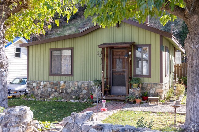 Green cottage with a stone-trimmed base, nestled amidst the trees in Lebec.