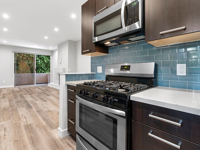 Blue tiled kitchen with stainless steel oven and microwave.