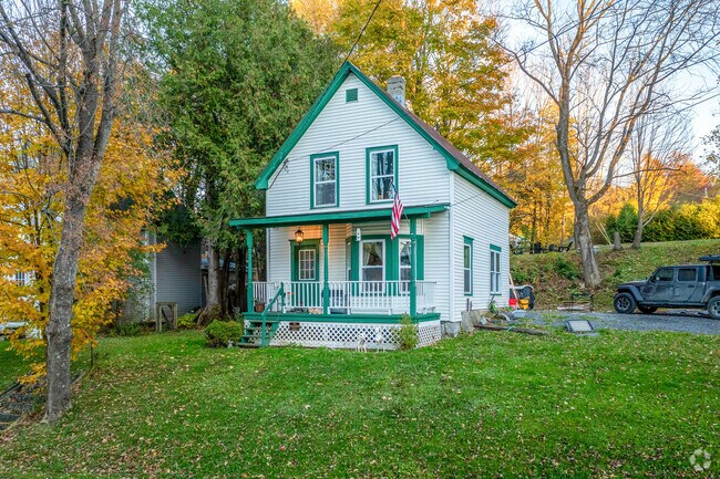 A white worker's cottage home in Graniteville has green accents surrounded by nature.