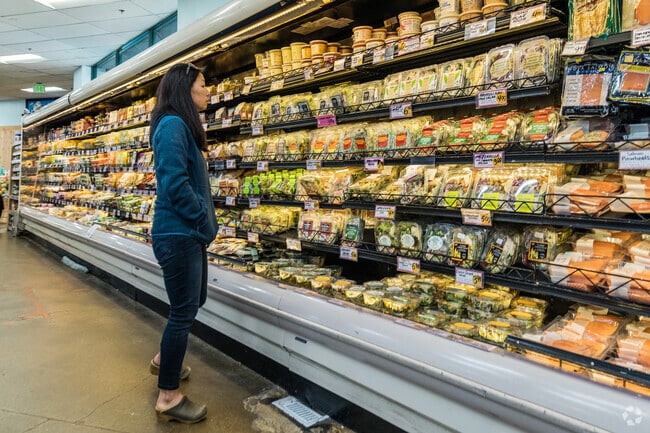 Trader Joe's shopper eyes the assortment of gourmet cheeses near Forestland.