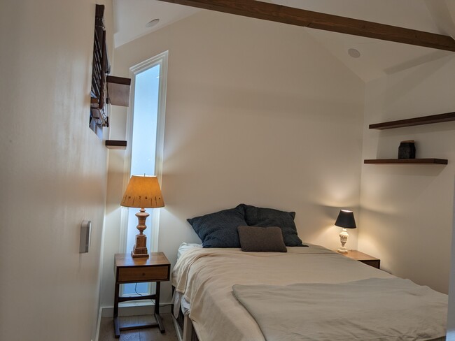 Bedroom furnished with dresser, bed with storage and hanging shelves.
