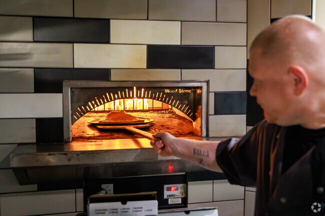 The Pizzaiolo puts a stromboli into the brick-fired oven at The Pizza Cutters in Lyncourt.