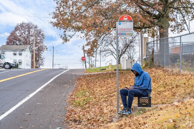 A man sits on a milk crate waiting for his bus to arrive in the Riverview neighborhood.