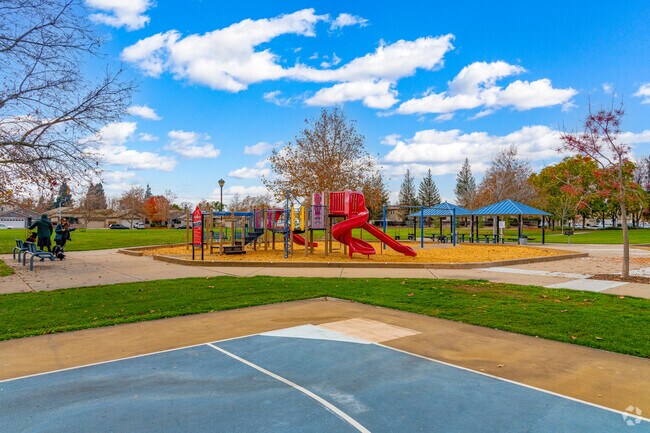 Couple sits with dogs on bench near playground at H. C. Elliott Park.