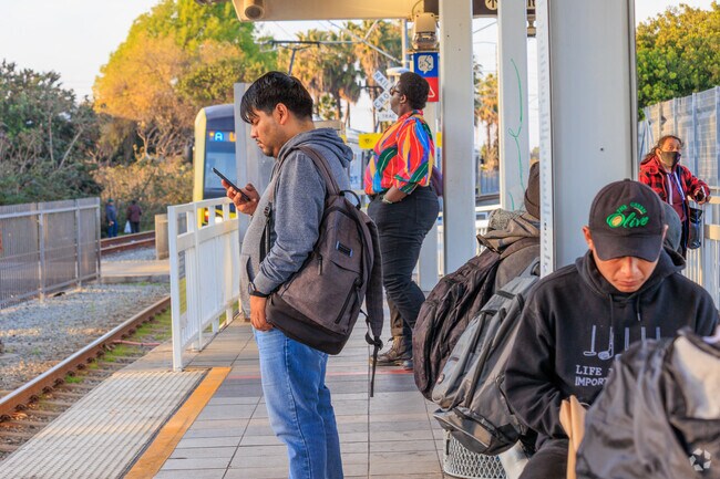 Passengers anticipate the train coming at the Metro station on Artesia.