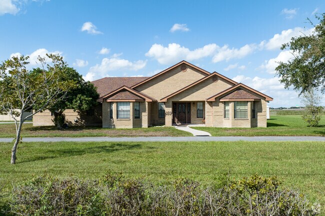 A single-family ranch-style home is located next to agricultural land in La Feria, Texas.