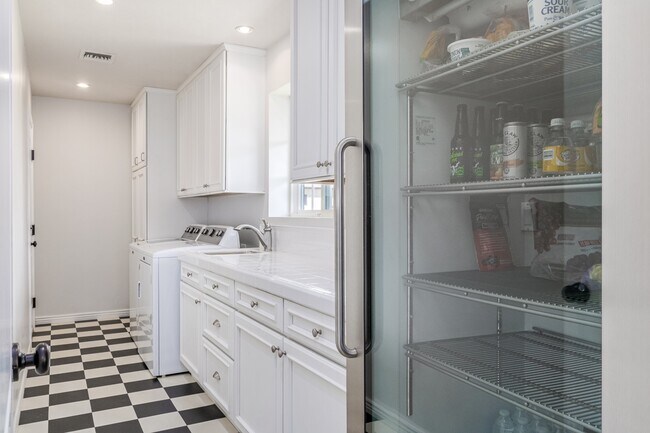 large open laundry room includes ample storage and full-size beverage cooler