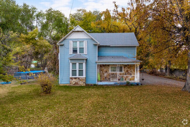 This quaint two story wood home is light blue and white and has stone details.