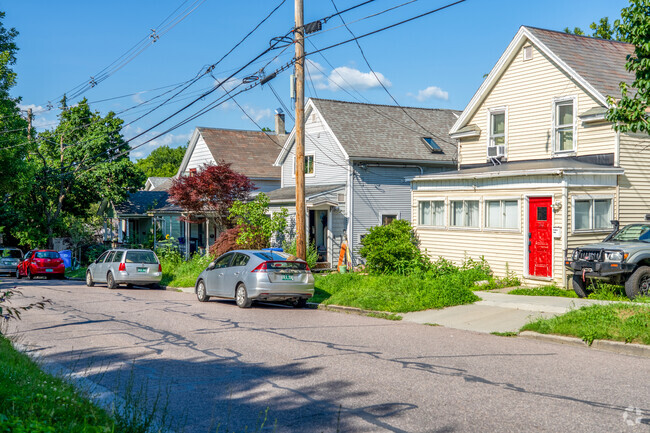 A row of colonial style homes are along a narrow street with lush greenery in Riverside.