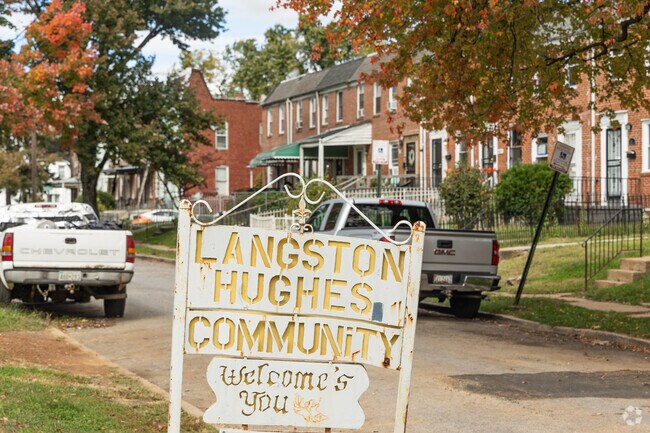 Langston Hughes community welcomes you, a rustic sign endures.