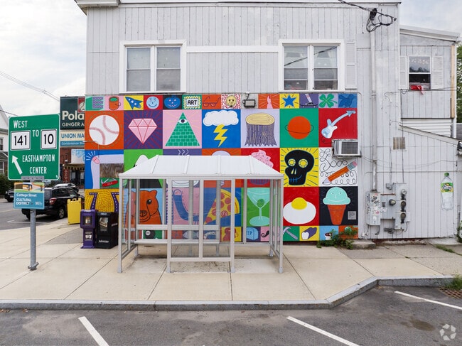 A colorful mural sits behind a bus stop in Easthampton.