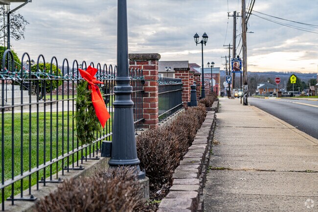 A fence with brick pillars runs along a sidewalk in the quiet area of Nicholson Township.