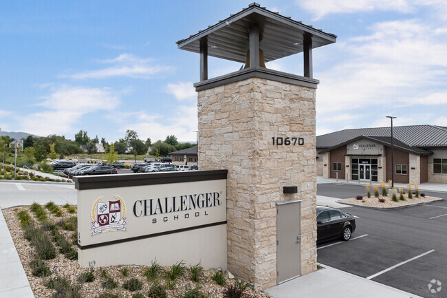 Challenger School has an off white sign attached to a stone column
