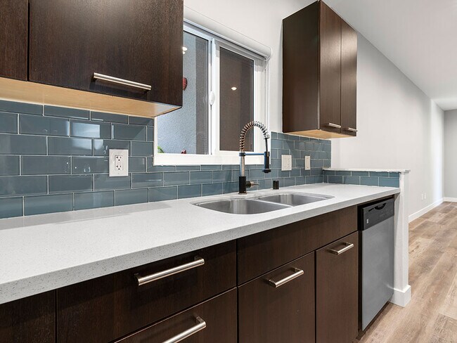 Blue tiled kitchen with stainless steel dishwasher.